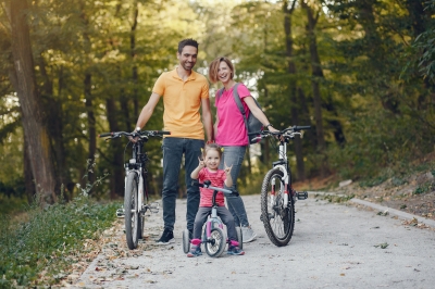 Familie mit Kleinkind stehen mit Fahrrädern am Waldweg