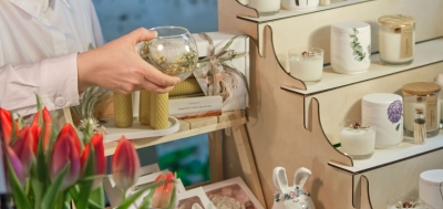 Dekoartikel stehen im Regal und eine Frau hält eine kleine runde Vase in der Hand