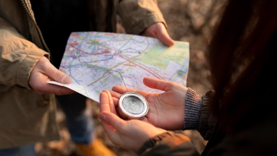 Wanderer mit Landkarte und Kompass zum Geocaching