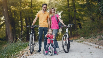 Eine Familien steht auf einem Waldweg und lächelt freundlich 