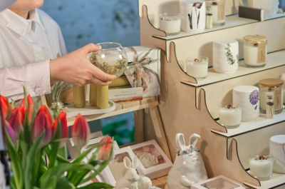 Dekoartikel stehen im Regal und eine Frau hält eine kleine runde Vase in der Hand